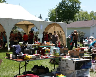 a group of people standing around a table with many items