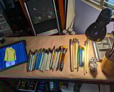 Art studio setup with iPad, brushes of all sizes, sketching pencils, pencile sharpener, paints, and light.