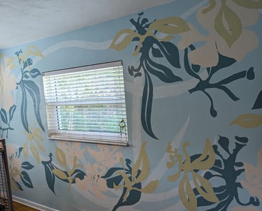 Using soft colors to layer multiple flower shapes on a large mural surrounding a window.