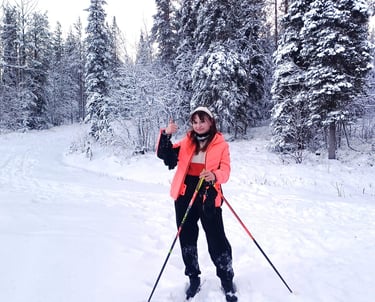 a woman in a pink jacket and black pants is standing in the snow with cross-country skis