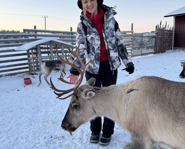 girl smiling while feeding reindeer