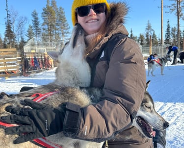 a woman in a yellow hat and a husky giving a kiss