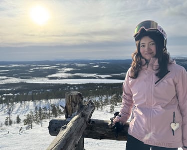 a woman in a pink jacket and helmet on a snowy day on top of a hill