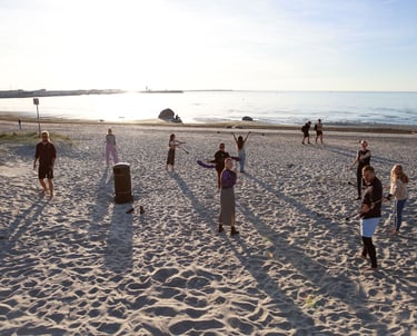Group of people practicing flow arts and drumming together on a sandy beach in Estonia. Photo by Martin Vähk