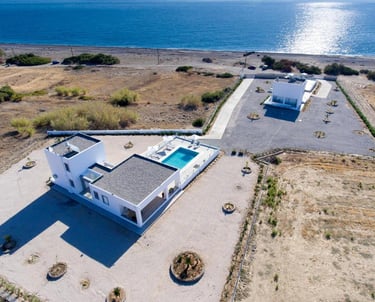 Aerial view of luxury white villas with private pools near the Mediterranean coast.