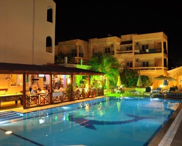 Night view of a lit outdoor swimming pool and poolside bar at a luxury Mediterranean resort hotel.