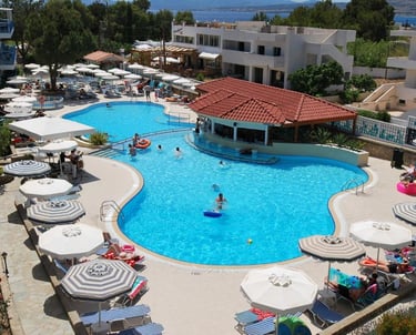 Luxury resort swimming pool with a swim-up bar, white umbrellas, and lounge chairs for summer vacation.