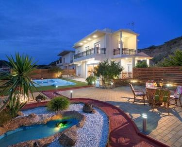 Luxury villa at twilight with a private swimming pool, garden pond, and outdoor dining area.