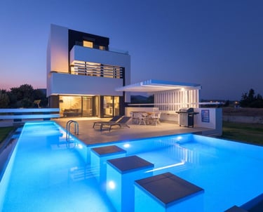 Modern luxury villa with a glowing blue swimming pool and outdoor patio at twilight.