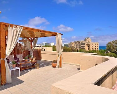 Luxury rooftop terrace with wooden pergola and sea view overlooking a Mediterranean coastal city.