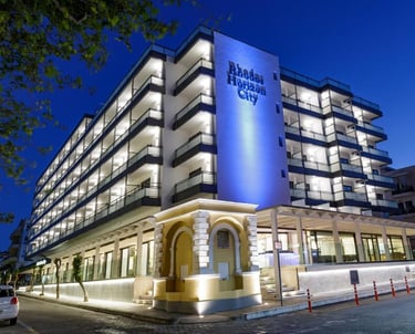 Modern facade of Rhodes Horizon City hotel with illuminated balconies at twilight in Greece.