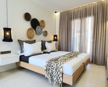 Modern boho bedroom with twin beds, woven wall decor, and black pendant lights.