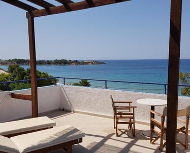 Sunny hotel balcony with lounge chairs and panoramic Mediterranean Sea views in Cyprus.