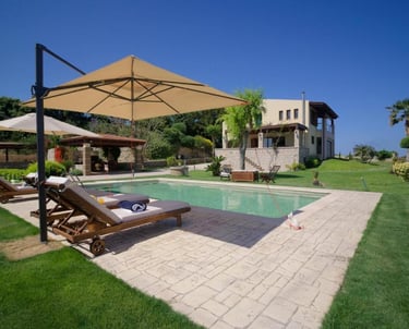 Luxury vacation villa with a private swimming pool, sun loungers, and patio umbrellas in a lush garden.