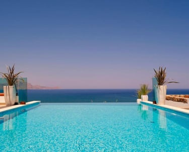 Luxury infinity pool overlooking the blue Mediterranean Sea at a summer vacation resort.