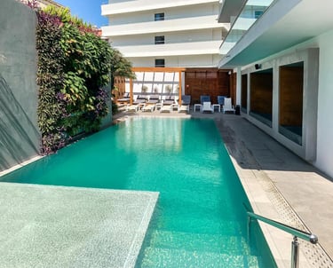 Luxury outdoor swimming pool at a modern hotel with a vertical garden wall and lounge chairs.