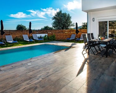 Luxury villa backyard with a swimming pool, sun loungers, and outdoor dining table.