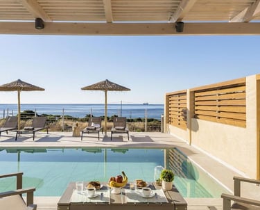 Luxury villa terrace with private infinity pool overlooking the ocean with lounge chairs.