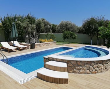 Luxury backyard swimming pool and integrated hot tub with wood deck and lounge chairs.