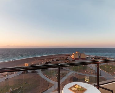 A sunset view of Rhodes beach and the aquarium from a luxury hotel balcony with wine and cheese.