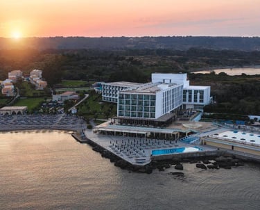 Aerial view of a luxury beachfront resort with a swimming pool at sunset.