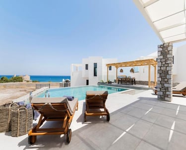 Luxury white villa with private infinity pool and sun loungers overlooking the blue ocean.