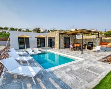 Luxury villa with private swimming pool, sun loungers, and stone patio dining area.