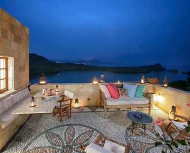 Luxury villa stone terrace with mosaic flooring overlooking a scenic bay at twilight.
