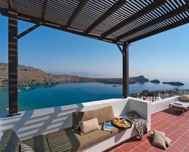 Luxury terrace with pergola and seating overlooking a scenic Mediterranean bay with blue water.
