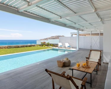 Luxury villa terrace with private infinity pool overlooking the blue ocean under a white pergola.