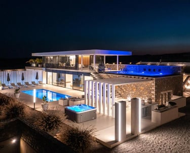 Luxury modern villa at night with illuminated infinity pool, hot tub, and outdoor terrace.
