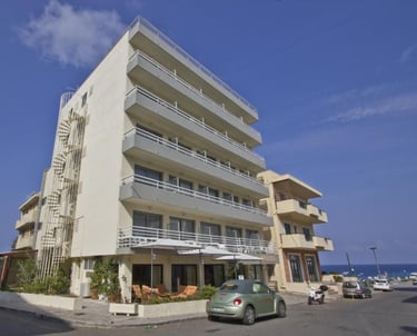 Multi-story beachfront hotel building with balconies near the sea in Rhodes, Greece.