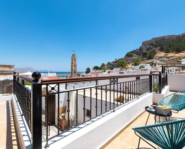 Luxury balcony in Lindos, Rhodes overlooking the historic village, church tower, and Acropolis.