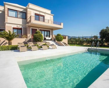Luxury modern villa with a turquoise swimming pool and sun loungers under a clear blue sky.