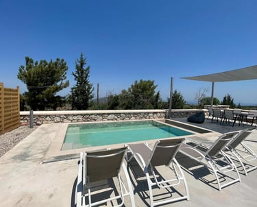 Luxury villa terrace with a private swimming pool, sun loungers, and outdoor dining area under a clear blue sky.