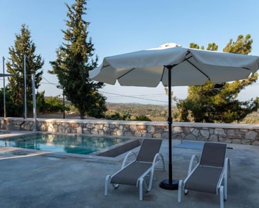 Luxury patio with lounge chairs, umbrella, and swimming pool overlooking a scenic valley landscape.