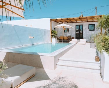 Luxury villa patio with a private infinity pool, sun loungers, and a shaded outdoor lounge area.