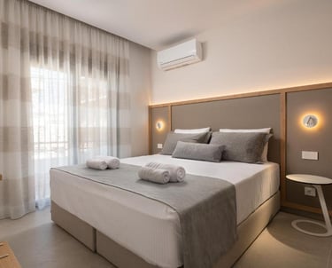 Modern hotel bedroom with a double bed, gray linens, and minimalist decor.
