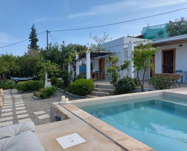 Luxury white villa with a small swimming pool and stone path in a Mediterranean garden.