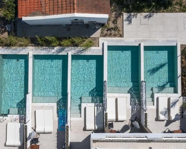 Aerial view of luxury apartment suites with private plunge pools and white sun loungers.