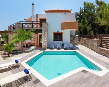 Luxury villa with private turquoise swimming pool, sun loungers, and stone patio area.