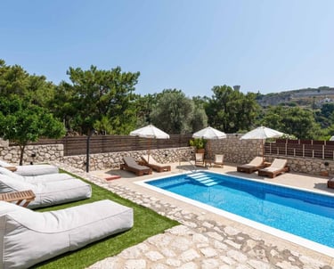 Luxury private villa with swimming pool, sun loungers, and bean bags on a sunny terrace.