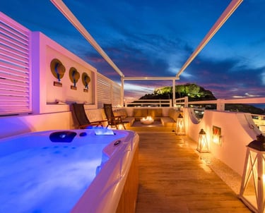Luxury rooftop terrace with hot tub and lounge seating overlooking a scenic sunset mountain.