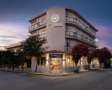 The exterior of City Plus Rhodes Hotel, a modern accommodation building at dusk.