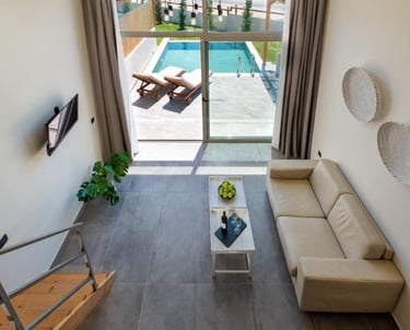 Modern luxury villa interior with a living room overlooking a private outdoor swimming pool.