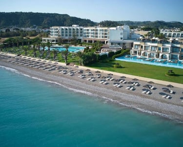 Aerial view of a luxury beachfront resort in Rhodes with swimming pools and a pebble beach.