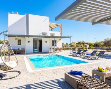 Luxury white villa with private swimming pool, sun loungers, and hanging egg chair.