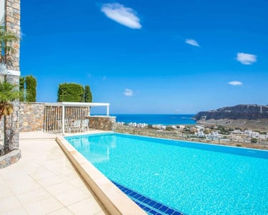Luxury infinity pool at a coastal villa overlooking the Mediterranean Sea and a scenic village.