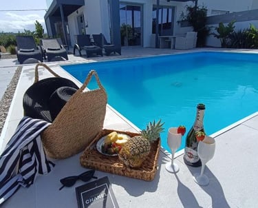 Luxury vacation scene with a swimming pool, champagne, and fresh fruit at a modern villa.