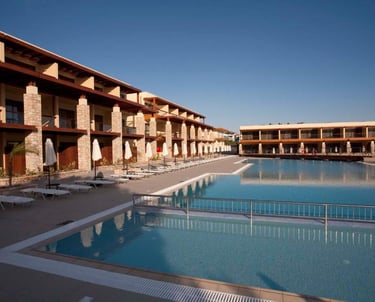 Luxury resort pool with lounge chairs and beach umbrellas near modern hotel buildings.